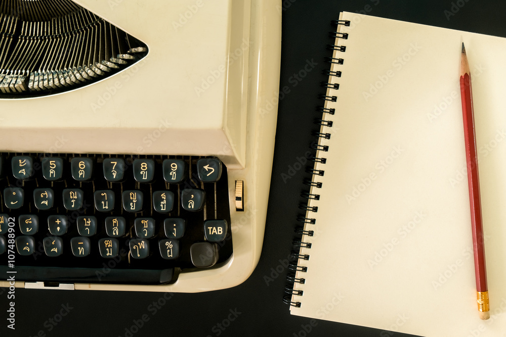Fototapete old typewriter and notebook on black table background