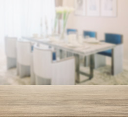 wooden table top with blur of dining table and comfortable chairs with elegant table setting