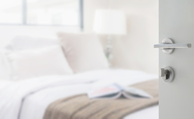 opened white door to bedroom with reading lamp and book