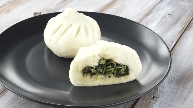 Rail motion video of Chines woman serve a plate of Chinese dumpling with vegetarian filling on a table.This video is about The door