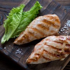 Close-up of grilled chicken breasts with fresh green salad