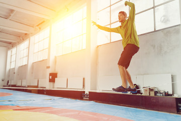 Man slacklining walking and balancing on a rope, slackline in a sports hall