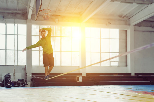 Man slacklining walking and balancing on a rope, slackline in a sports hall