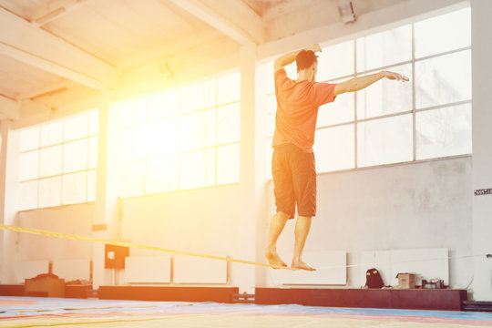 Man slacklining walking and balancing on a rope, slackline in a sports hall