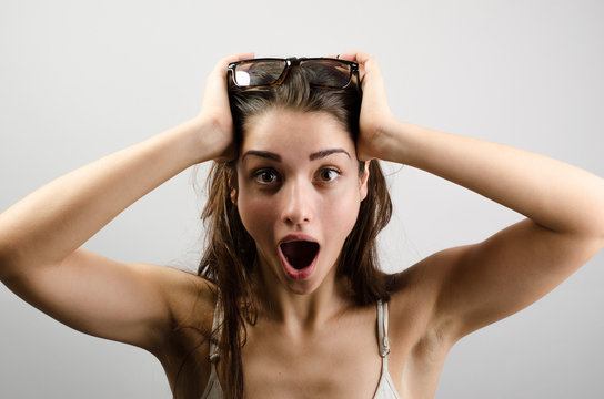 Close-up portrait of surprised beautiful girl holding her head in amazement and open-mouthed