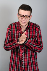 Portrait of young man rubbing palm crafty and cunning on gray background