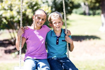 Obraz premium Siblings sitting on a swing in the park