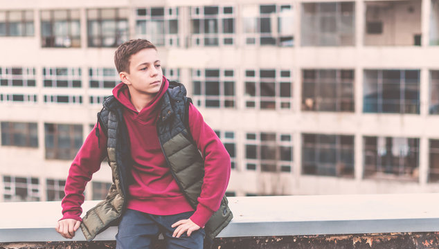 serious teenager sitting on the roof of the house