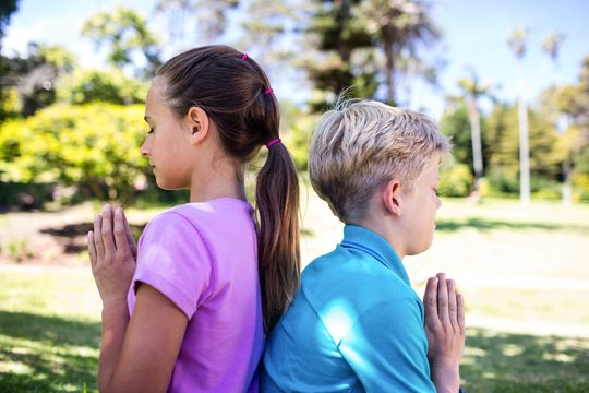 Siblings praying in park