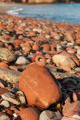 Red Stone with hole (adder stone or Hen`s got) on rocky sea coast.