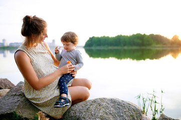 Young pregnant mother resting with her son in summer park 