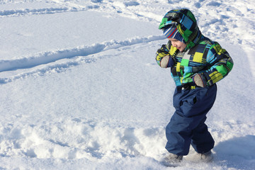 Fototapeta na wymiar The child in a color jacket running on snow in the winter