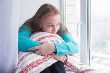 teenage girl sits by the windowsill and looking out window