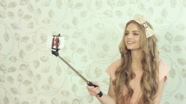 Cute girl with a large bouquet of roses doing selfie using a monopod in the studio 