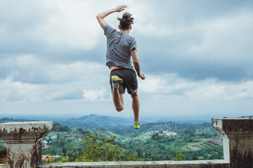Hipster traveler jumping against the mountains, Bali