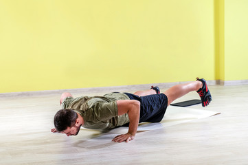 Handsome young man at gym, exercising with friction pads.