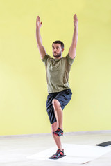 Handsome young man at gym, exercising with friction pads.