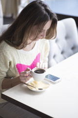 Young girl, sitting in a cafe with cup of coffee 