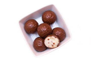 Chocolate pralines on a square bowl on a white background seen from above