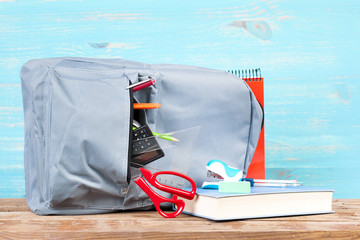Backpack with school tools on turquoise background