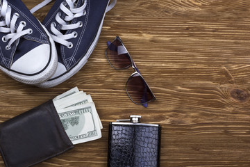 Men's accessories: wallet, sunglasses, flask and sneakers.