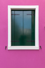 Old window with dark green shutters on pink (fucsia) wall