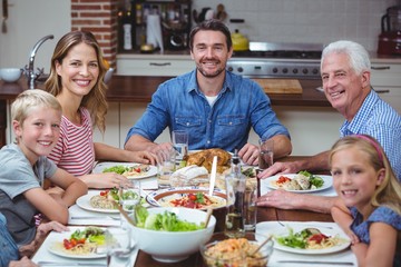 Smiling multi generation family sitting at dining table