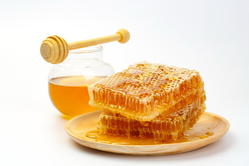 Honeycomb with jar and honey dipper isolated on white background