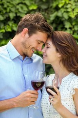 Couple holding wineglasses with eyes closed at front yard