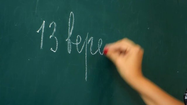 Teacher writes on the chalk blackboard on 13 September