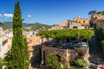 Fototapeta na wymiar Sunny view of tower and terrace cafe in fortress Tossa de Mar, Girona province, Spain.