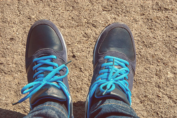 Young man wearing sport shoes with blue shoelace and jeans