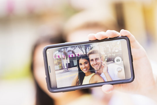 Close up of Hispanic couple taking selfie outdoors