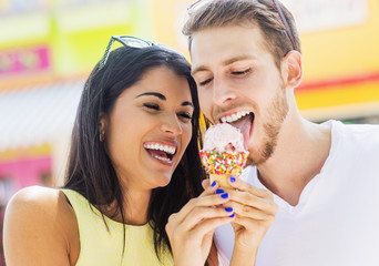 Hispanic couple sharing ice cream cone outdoors
