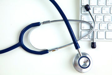 A medical stethoscope near a laptop on table