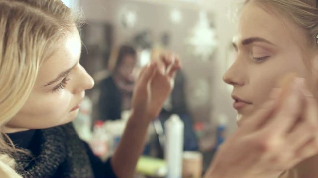 Visagist powders the model's face 