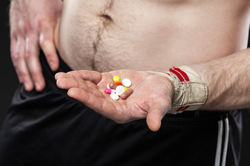 Young man holding a pill on black background.