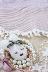 White brooch like head of hare with pink and white bracelets on pink lace as background