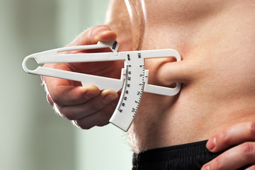 Man is measuring his body fat with calipers..
