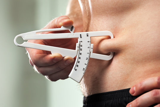 Man Is Measuring His Body Fat With Calipers..