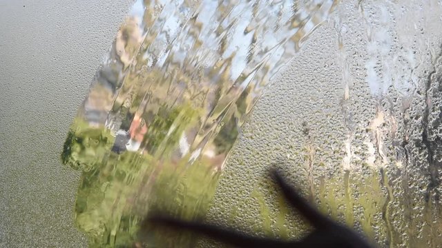 Une main nettoie la vitre embu&eacute;e
