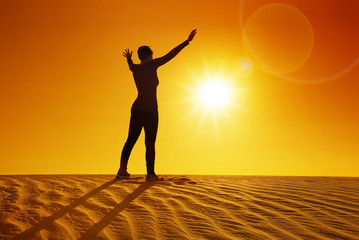 Fototapeta na wymiar female silhouette on top of sand dune at sunset