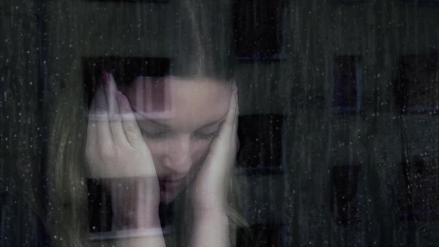 Sad young woman.
Young woman looking out of a window a rainy day, looking thoughtful and lonely. Heavy rain pouring down.