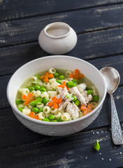 Chicken soup with vegetables and pasta on a dark wooden background