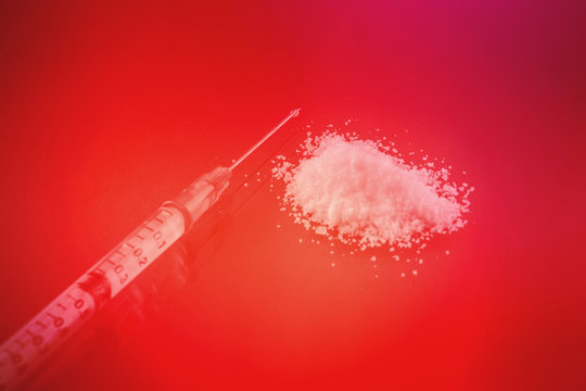Drug Syringe And Heroin Powder With Danger Color Concept.