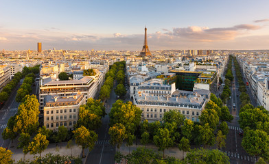 Fototapeta premium Paryż z góry prezentujący dachy, Wieżę Eiffla, wysadzane drzewami aleje z haussmannowskimi budynkami oświetlonymi przez zachodzące słońce. Avenue Kleber, Avenue d'Iena i Avenue Marceau, 16. dzielnica