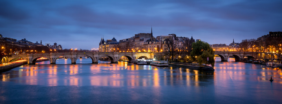 Dawn on a cloudy morning in Paris, with Ile de la Cite, Pont Neuf and the Seine River reflecting city lights. France