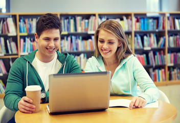 happy students with laptop in library