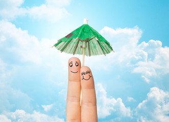 close up of two fingers with cocktail umbrella