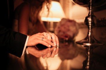 Romantic newlywed couple posing in hotel room, hands closeup
